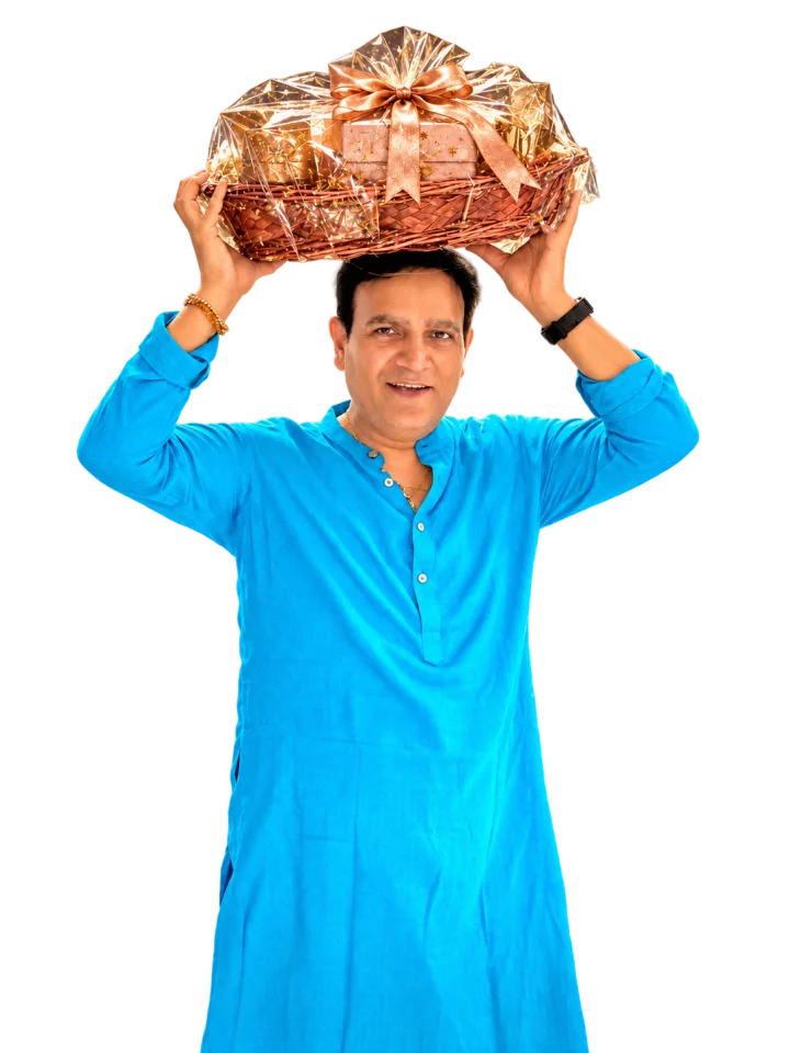 Nirbhay Singh in a bright blue kurta holding a rose-gold gift hamper above his head